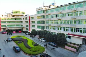 Un edificio de varios pisos con un patio central, zona de estacionamiento y un elemento vertical rojo.