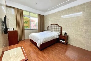 A hotel room with a bed, a desk, a chair, a TV, and a window with curtains. - Ganzhou Hotel (Ganzhou)