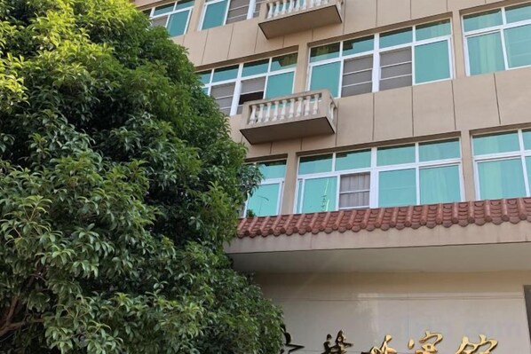 A multi-story building with balconies and a tree in the foreground. - Ganzhou Hotel (Ganzhou)