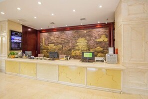 A reception desk with a digital screen, a computer, and a phone. - Ganzhou Hotel (Ganzhou)