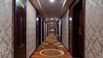 Un pasillo de hotel con papel tapiz estampado, puertas de madera y suelo alfombrado.