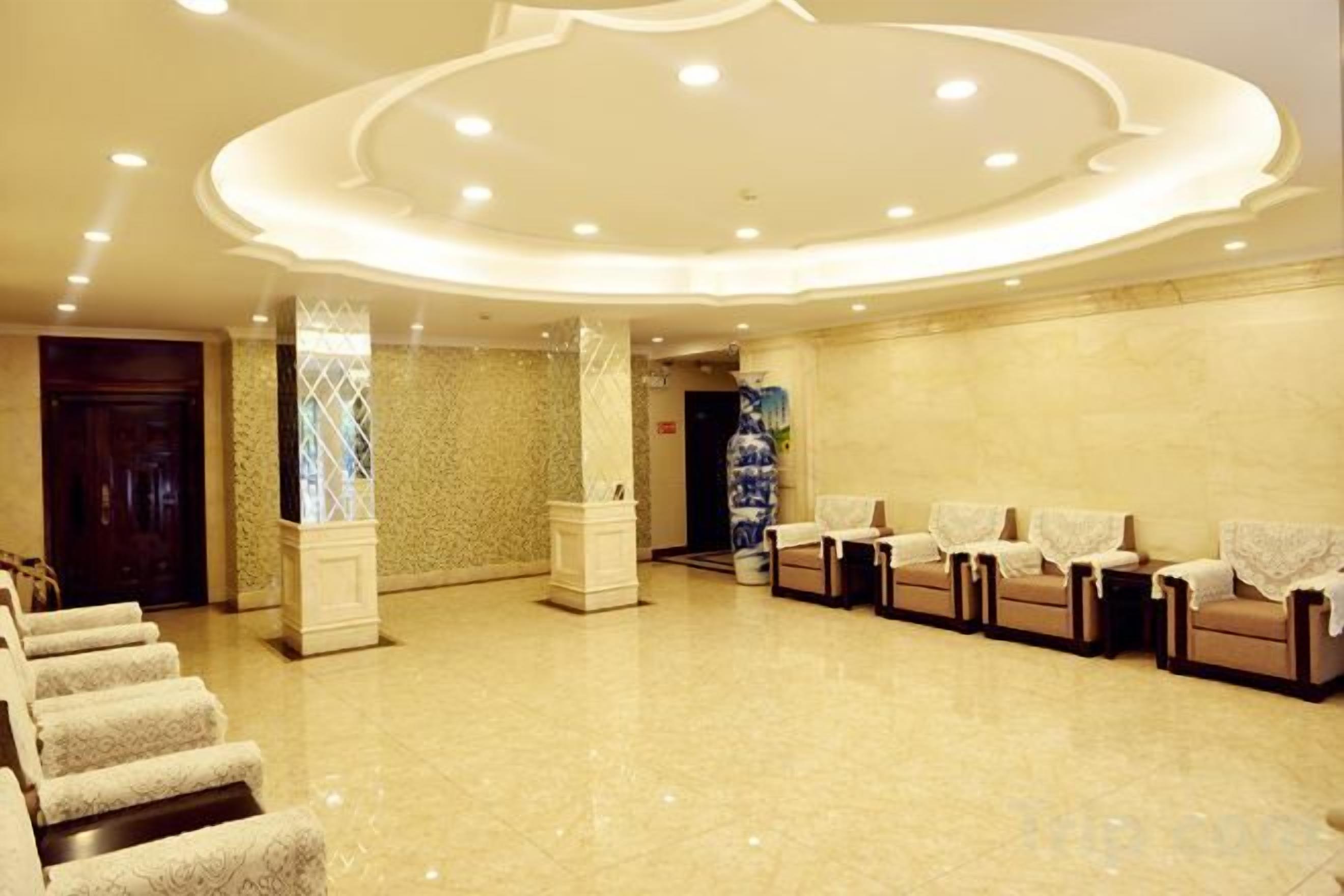 A hotel lobby with a reception desk, seating area, and a decorative ceiling.