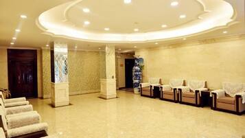 A hotel lobby with a reception desk, seating area, and a decorative ceiling.
