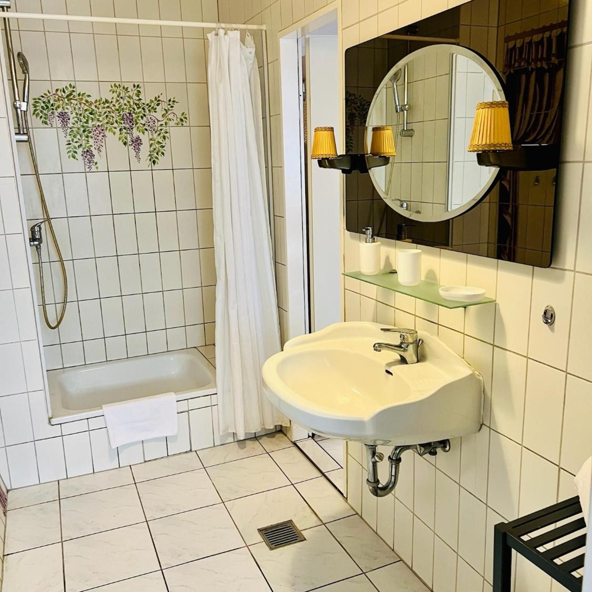 Un baño con bañera, ducha, lavamanos y espejo.