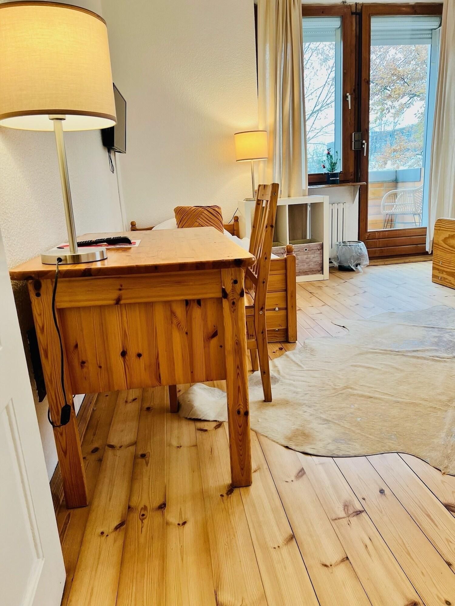 Ein Holzespeisesaal mit Stühlen, einer Lampe und Blick ins Freie durch eine Tür.
