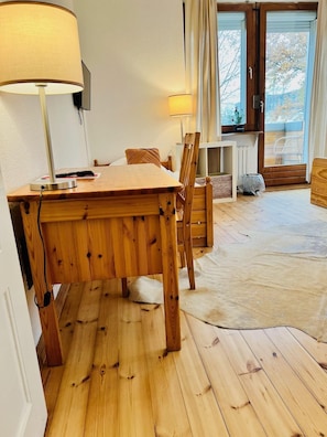 Una mesa de madera para comer con sillas, una lámpara y vistas al exterior a través de una puerta.