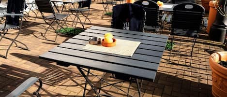 An outdoor seating area with tables and chairs, some with cushions.
