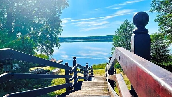 A wooden staircase leading to a dock over a calm lake, surrounded by trees.