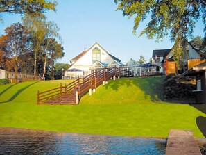 A hotel with a prominent building, a wooden staircase, and a grassy area.