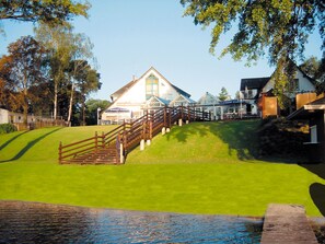 Ein Haus mit einer markanten Treppe, die zu einer Terrasse führt, umgeben von üppiger Vegetation und blauem Himmel.