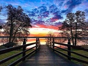A wooden boardwalk leading to a body of water with trees on either side.