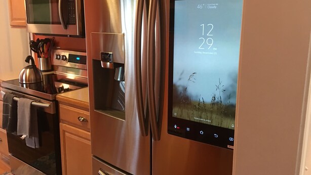 A stainless steel refrigerator with a digital display showing the time and date, a microwave above it, and a kettle on the stove. - Upscaled Home in a Quiet Neighborhood (Springfield)