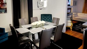 A modern dining area with a glass table, black chairs, and a teal upholstered chair. - Upscaled Home in a Quiet Neighborhood (Springfield)
