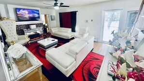 A living room with a TV, fireplace, white sofas, and a red rug. - Upscaled Home in a Quiet Neighborhood (Springfield)