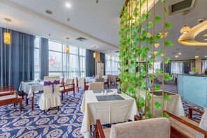 Un espace de restauration d’hôtel avec des tables, des chaises et un jardin vertical.