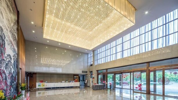 Eine geräumige Lobby mit hoher Decke, einem Empfangsbereich und großen Fenstern für natürliches Licht.