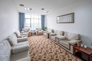 Un salon spacieux agrémenté d’un tapis à motifs, de plusieurs canapés, d’une table basse et d’une œuvre d’art encadrée accrochée au mur.