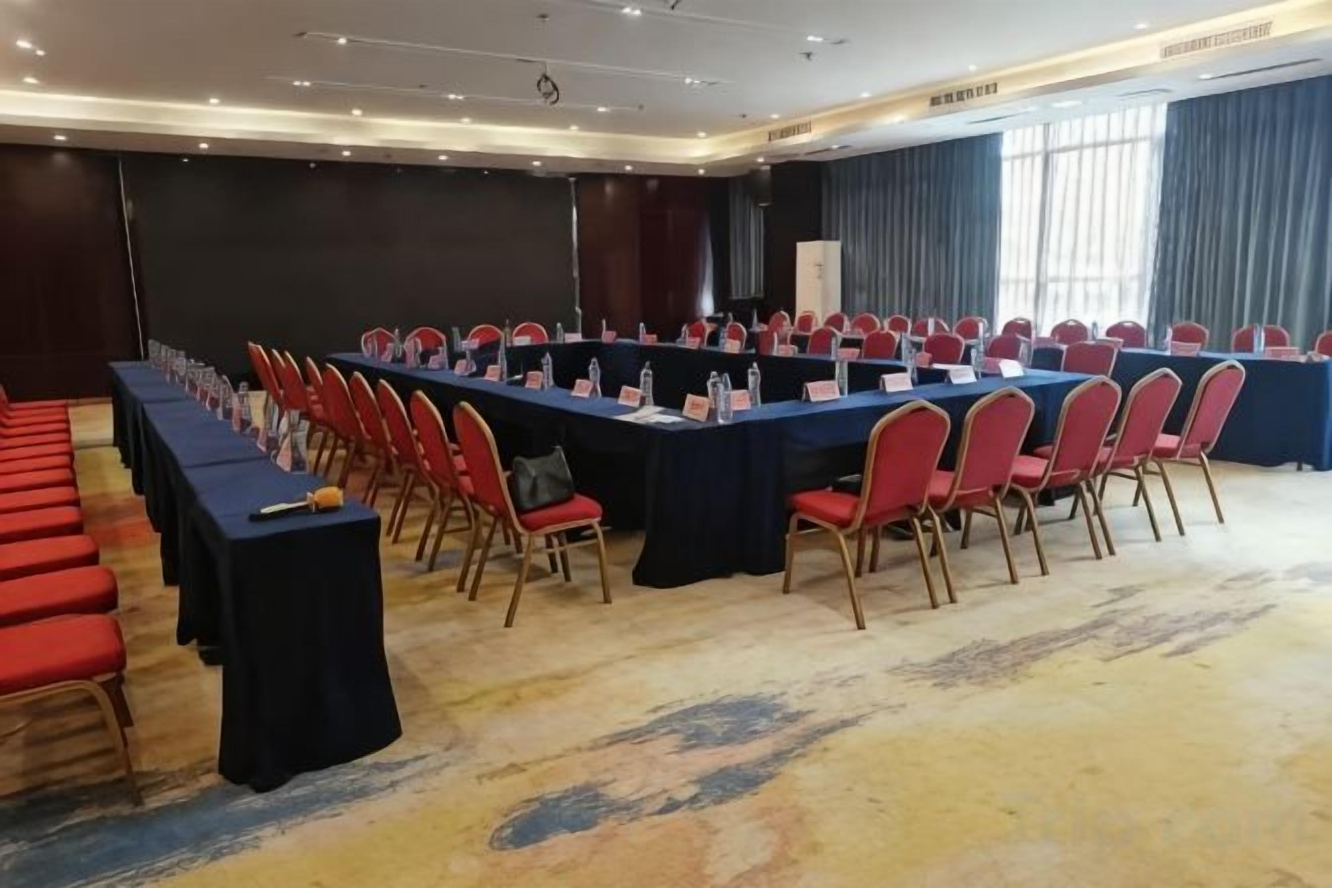 A conference room with a long table, red chairs, and a carpeted floor.