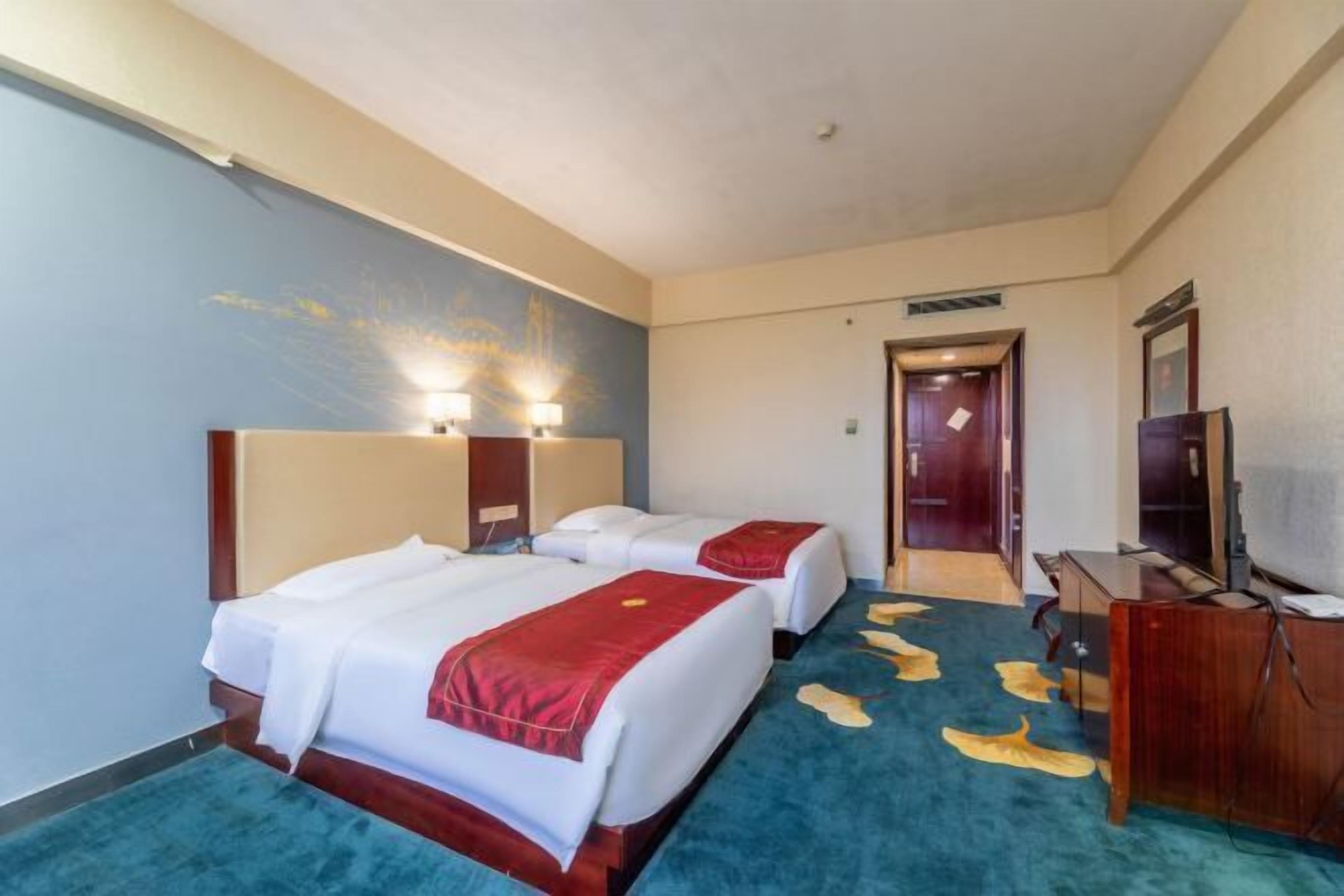 A hotel room with two beds, a TV, and a desk.