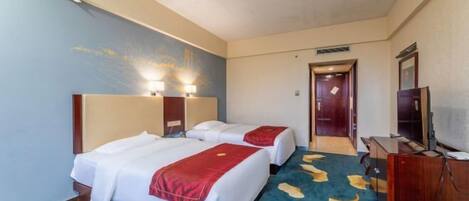 A hotel room with two beds, a TV, and a desk.