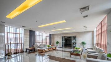 A spacious lobby with a reception desk, seating area, and large windows.
