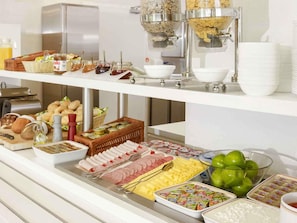 A buffet with various food items including bread, pastries, meats, cheeses, and condiments. - Ibis Budget Wroclaw Poludnie (Wroclaw)