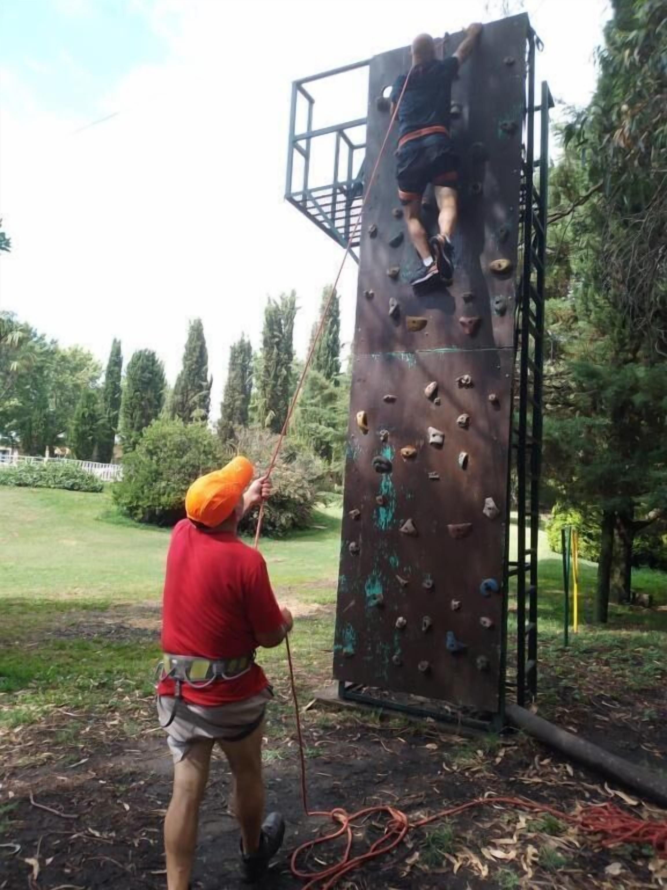 Una persona escalando una pared de metal al aire libre.