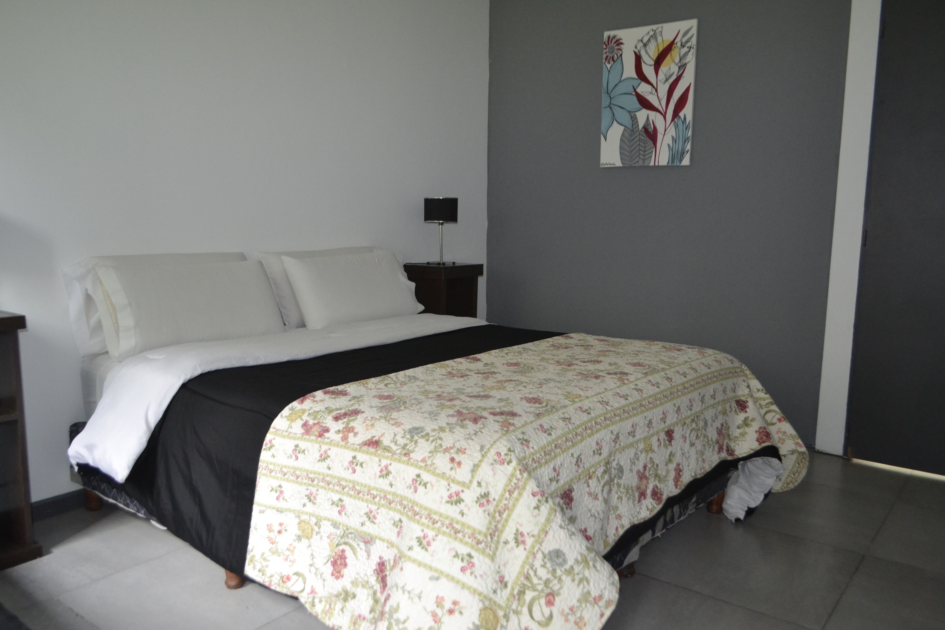 A bedroom with a bed, a nightstand, and a wall-mounted lamp.