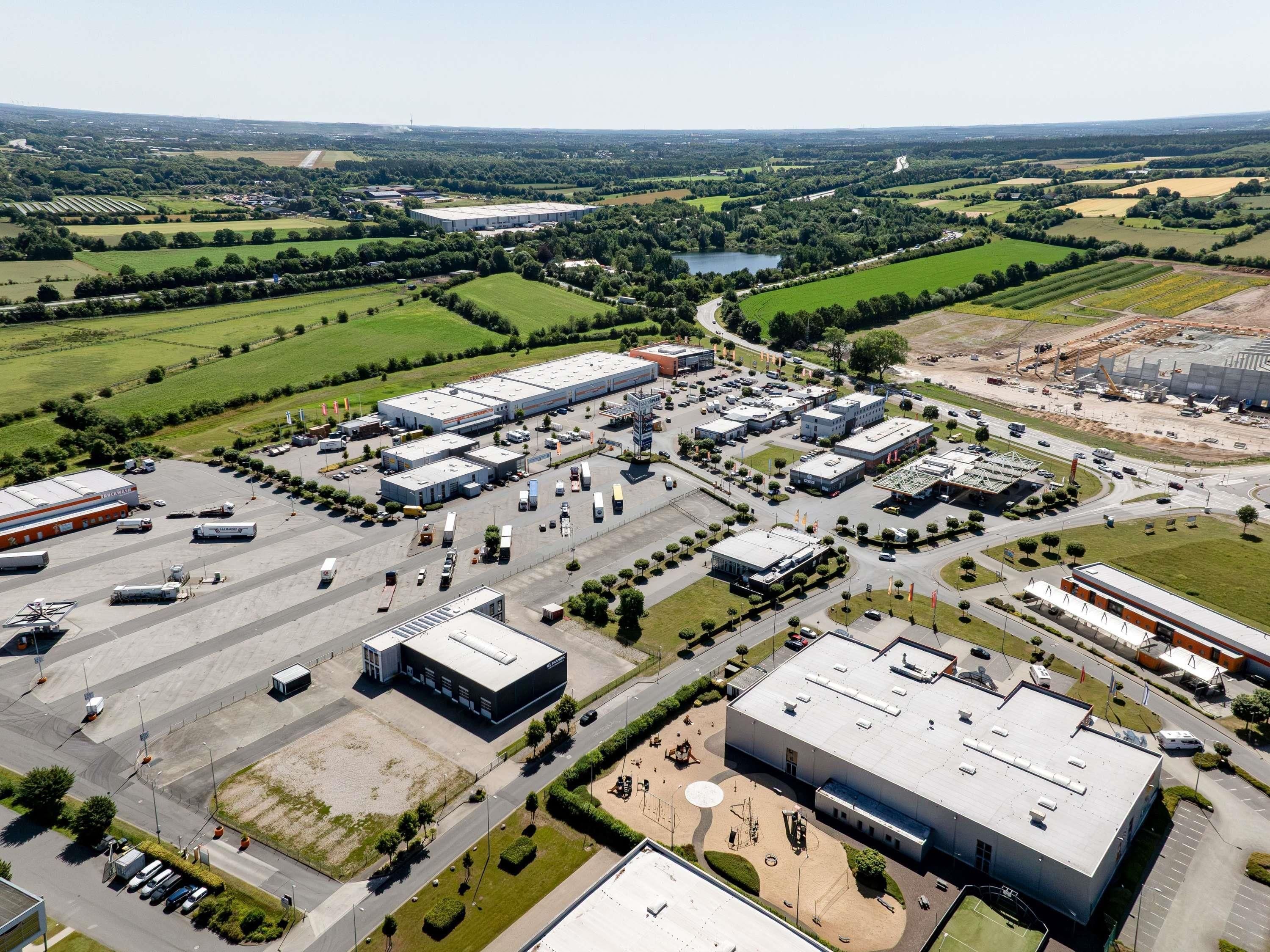 Une zone industrielle comprenant plusieurs bâtiments, des parkings et un vaste espace ouvert avec un petit lac.