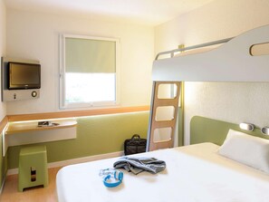 Une chambre avec un lit superposé, une télévision, un bureau et une fenêtre.