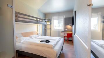Una habitación de hotel compacta con una cama litera, un escritorio, una silla y un televisor.