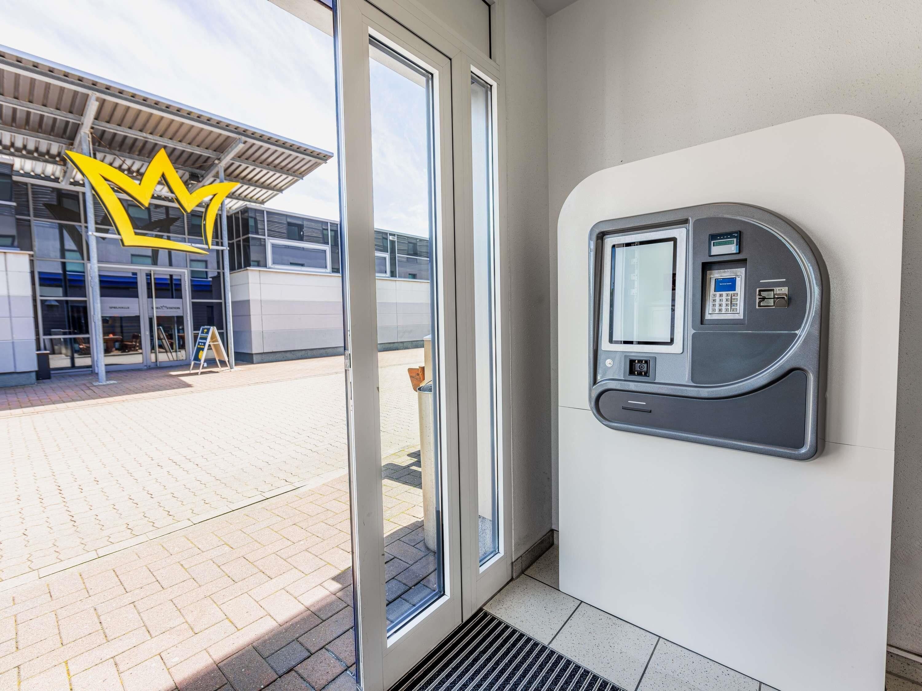 A modern building entrance with a glass door, a payment kiosk, and a clear view of the building's exterior.