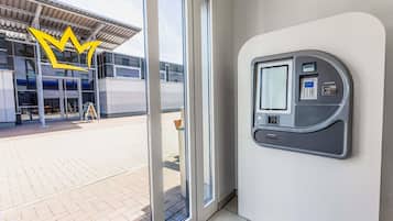 A modern building entrance with a glass door, a payment kiosk, and a clear view of the building's exterior.