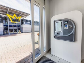 A modern building entrance with a glass door, a payment kiosk, and a clear view of the building's exterior. - Ibis Budget Flensburg Handewitt (Handewitt)