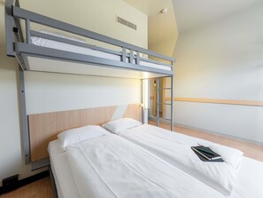 Un lit superposé avec une tête de lit en bois, une table de chevet avec un livre, et un luminaire fixé au mur.
