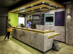 Modernilla designilla varustettu vastaanottotiski, jossa on yhdistelty betonia ja puuta, suuri ikkuna ja digitaalinen näyttö.