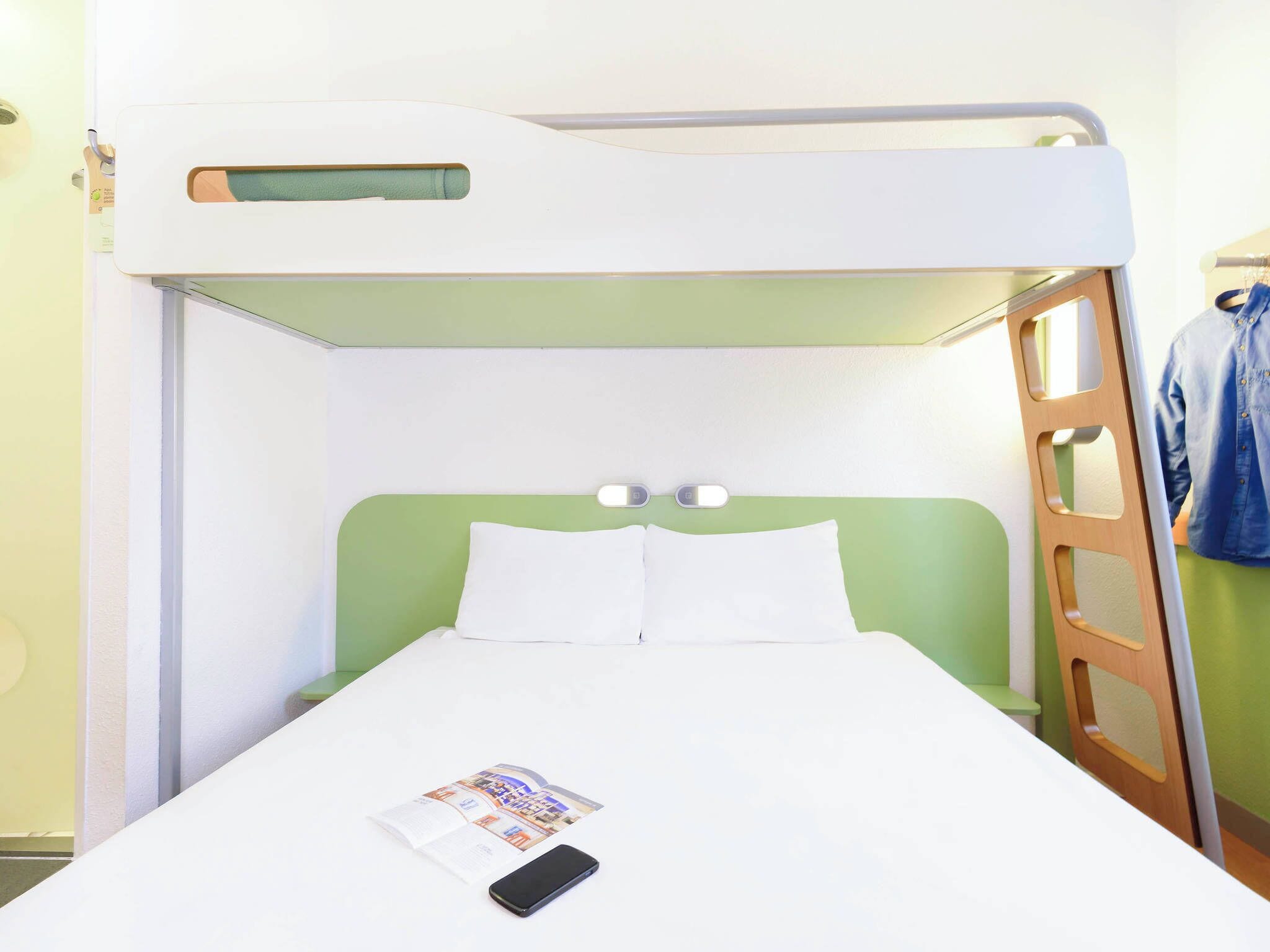 A bunk bed with a green headboard, a white mattress, and a magazine on the bed.