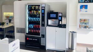 Una macchina distributrice automatica con erogatore di bevande e scelta di snack.