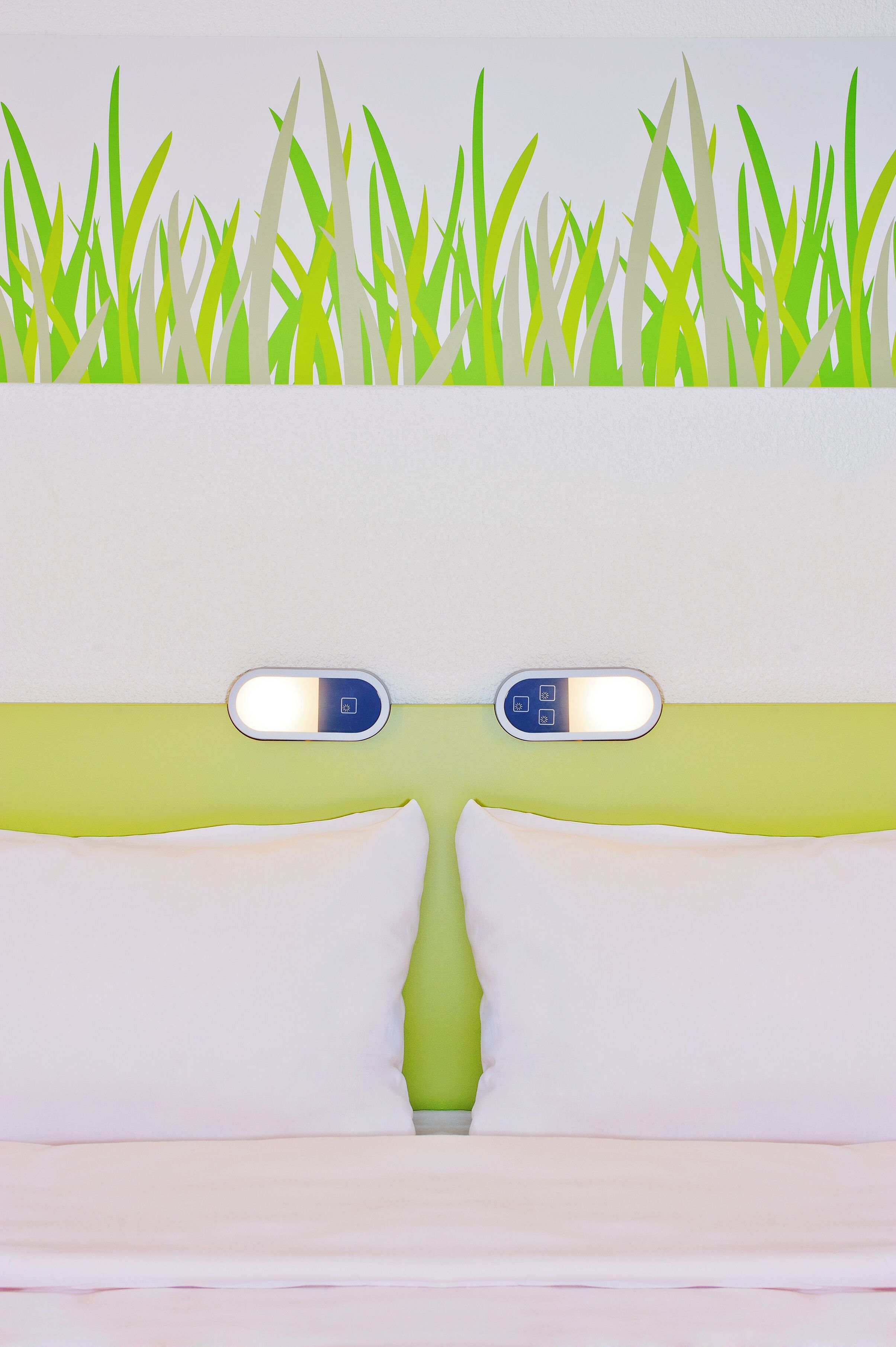 Ein Zimmer mit Grün-Weiß-Farbgestaltung, einem Bett mit weißer Bettwäsche und einem an der Wand montierten Thermostat.