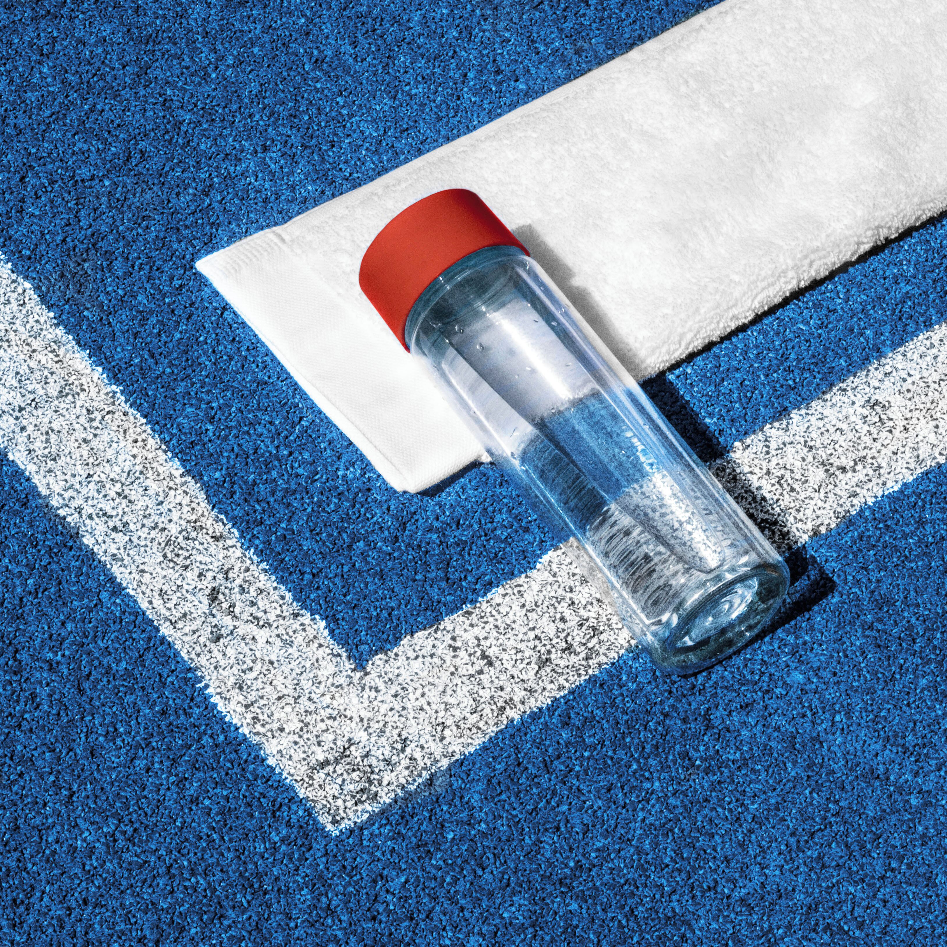 Une place de stationnement bleue, délimitée par une ligne blanche, et un bouchon rouge sur une bouteille transparente.
