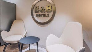 A B&B hotel reception area with two white armchairs and a small round table. - B&B HOTEL Ingolstadt-Lenting (Lenting)
