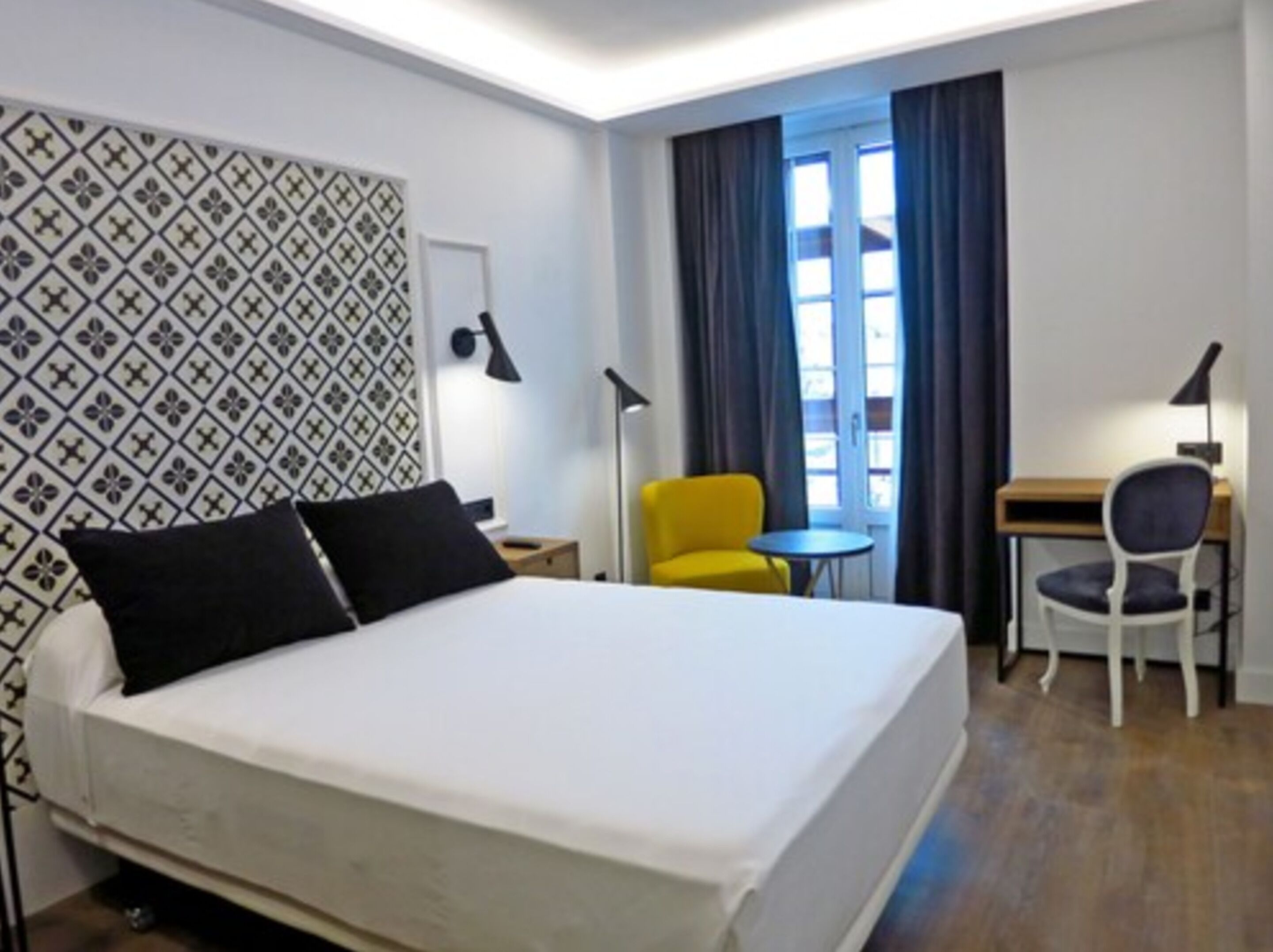 Una habitación de hotel con una cama, un escritorio, una silla y una mesita.