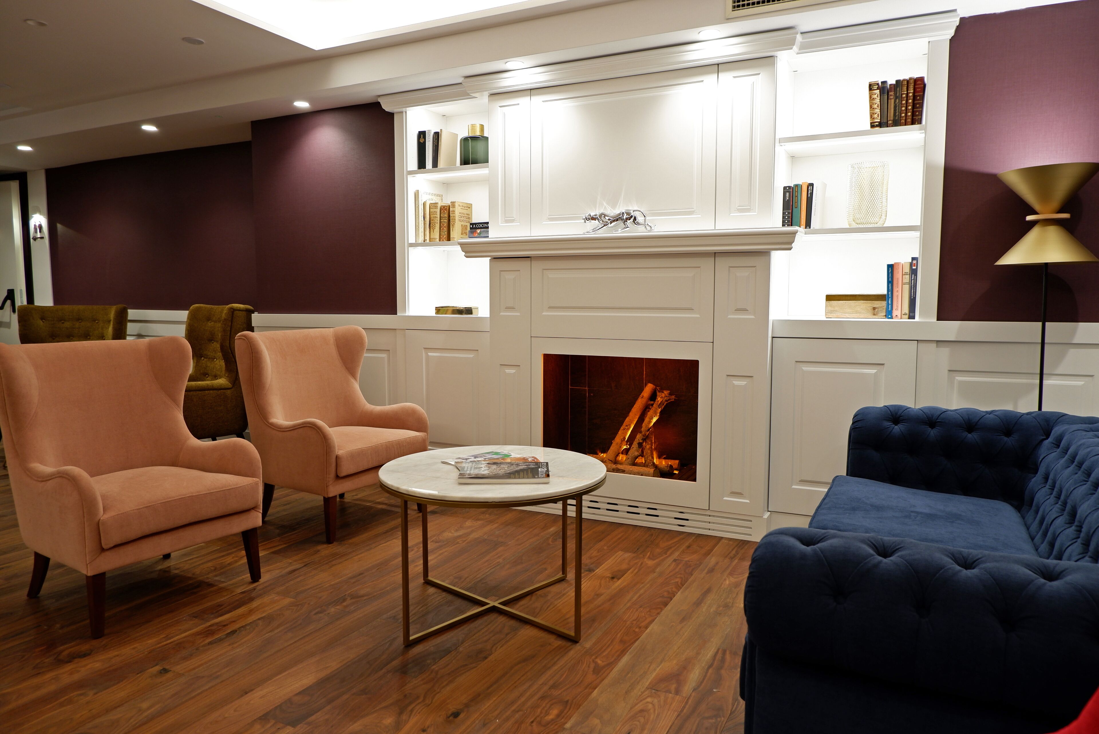 Una sala de estar moderna con chimenea, piso de madera y una combinación de sillones y sofás.