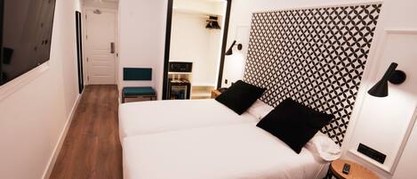 A hotel room with a large bed, a small table, a mirror, and a TV.