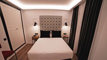 Een hotelkamer met een groot bed, twee nachtkastjes met lampen, een kledingkast en een rode stoel.