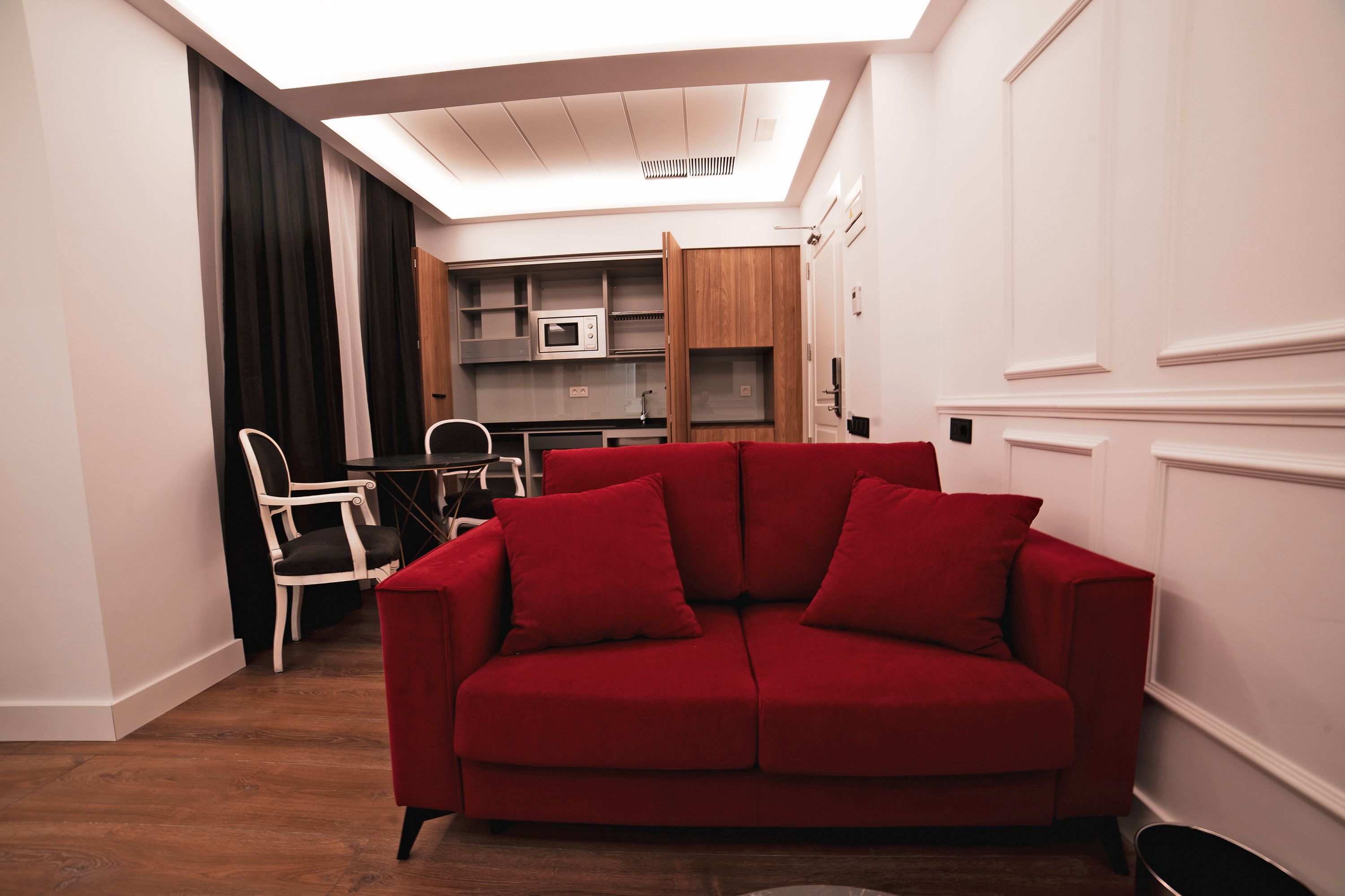 Una sala de estar moderna con un sofá rojo, suelo de madera y un tragaluz.