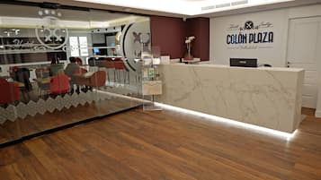 Un área de recepción con mostrador de mármol, pared de vidrio con diseño decorativo y suelo de madera.