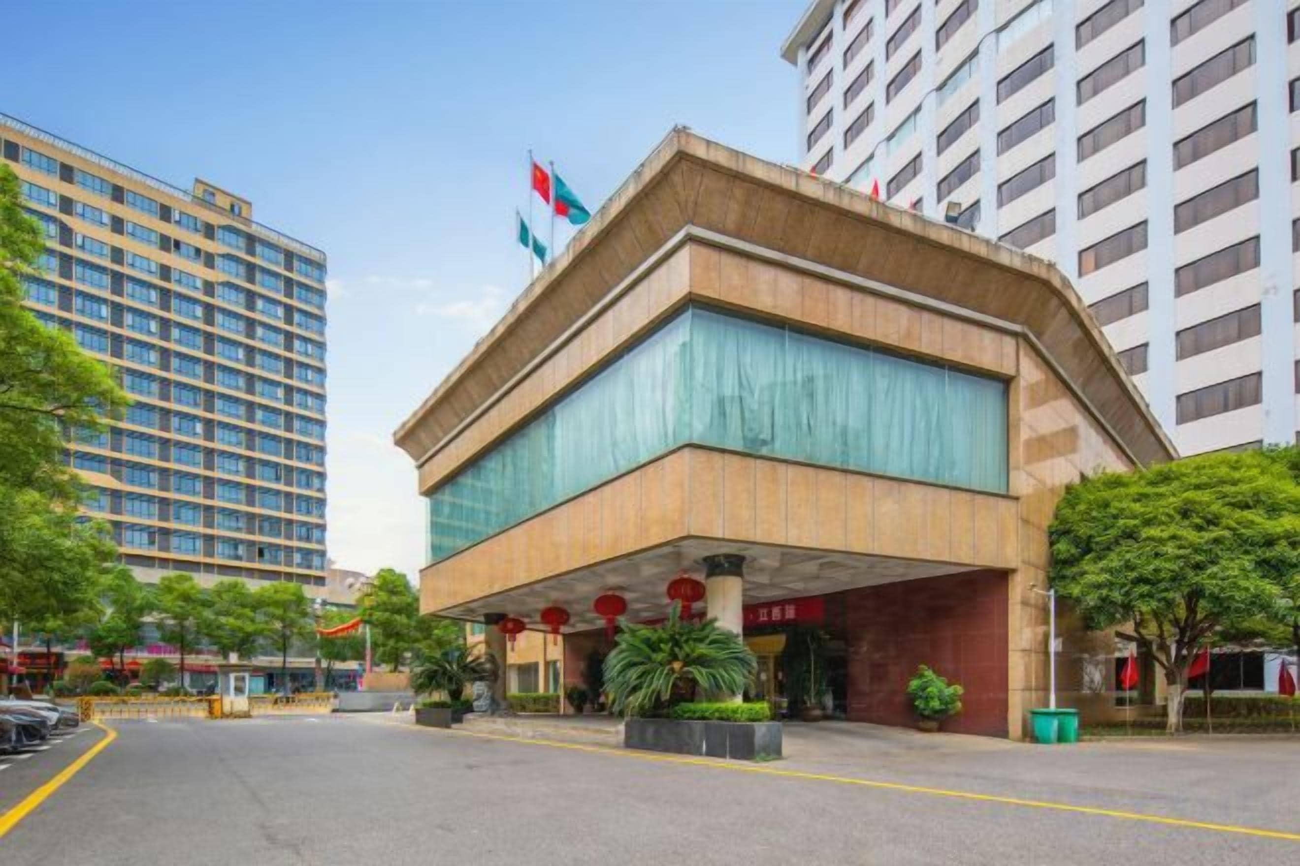 Un hôtel au design moderne, doté d’une entrée imposante avec un espace abrité et un drapeau au sommet.