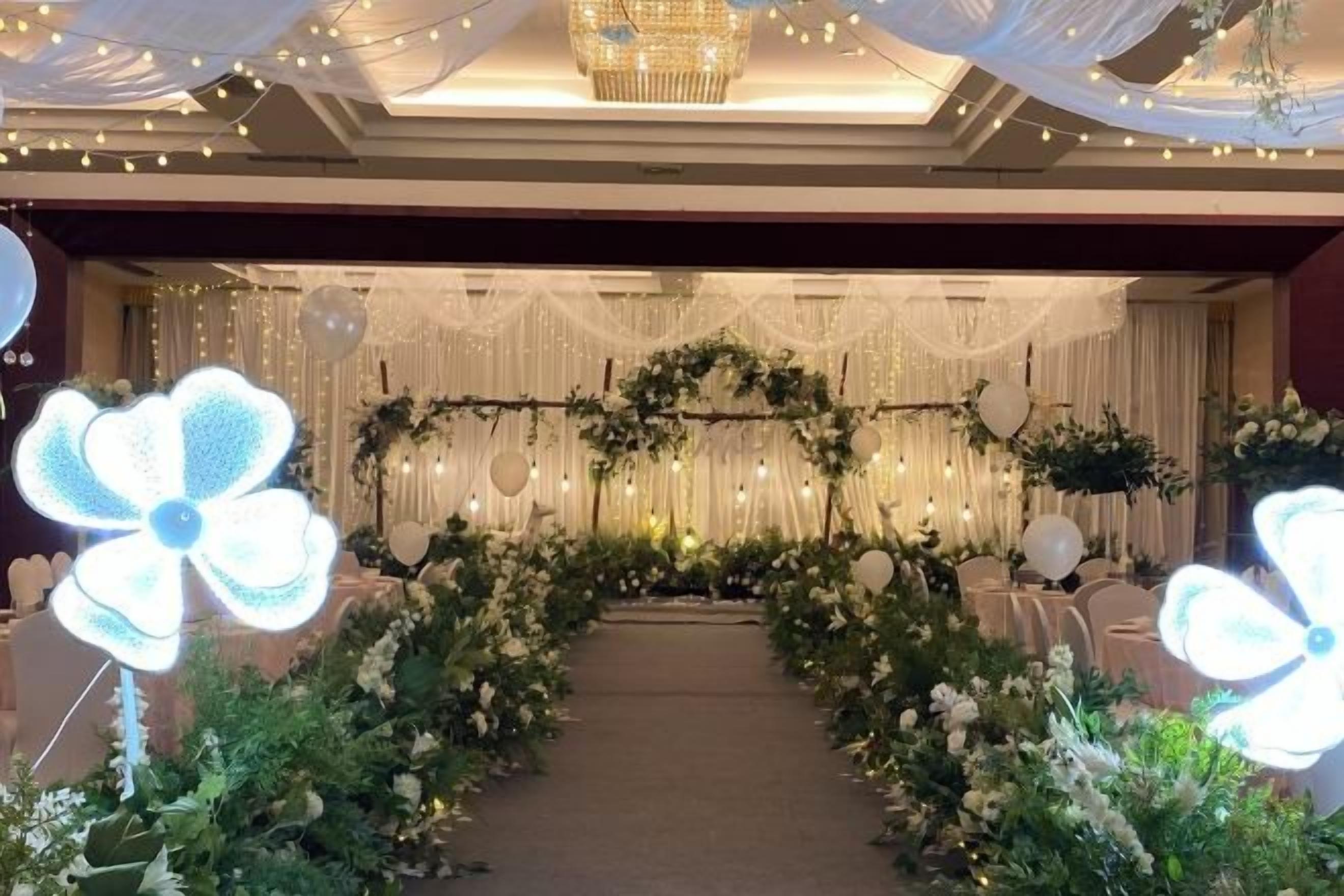A decorated aisle with floral arrangements and a chandelier.