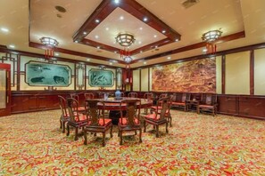 A conference room with a round table and chairs, a patterned carpet, and traditional wall art. - Huaqiao Hotel (Yingtan)